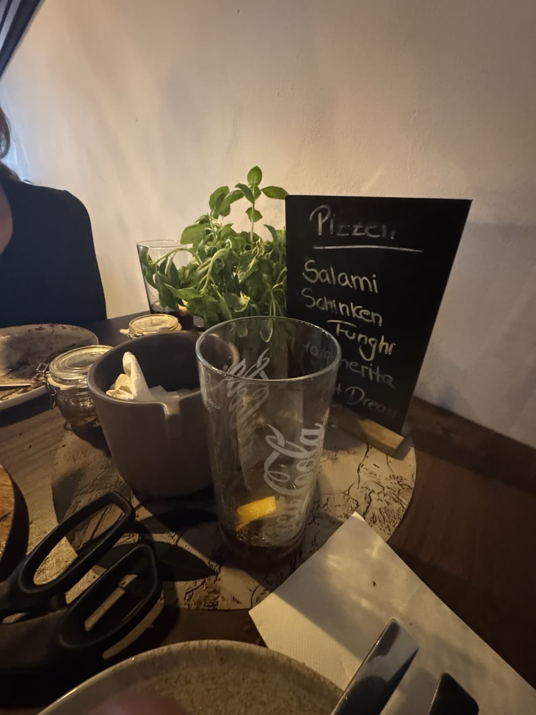 Basilikumpflanze und Kreidetafel mit Pizzen des Tages auf dem Tisch